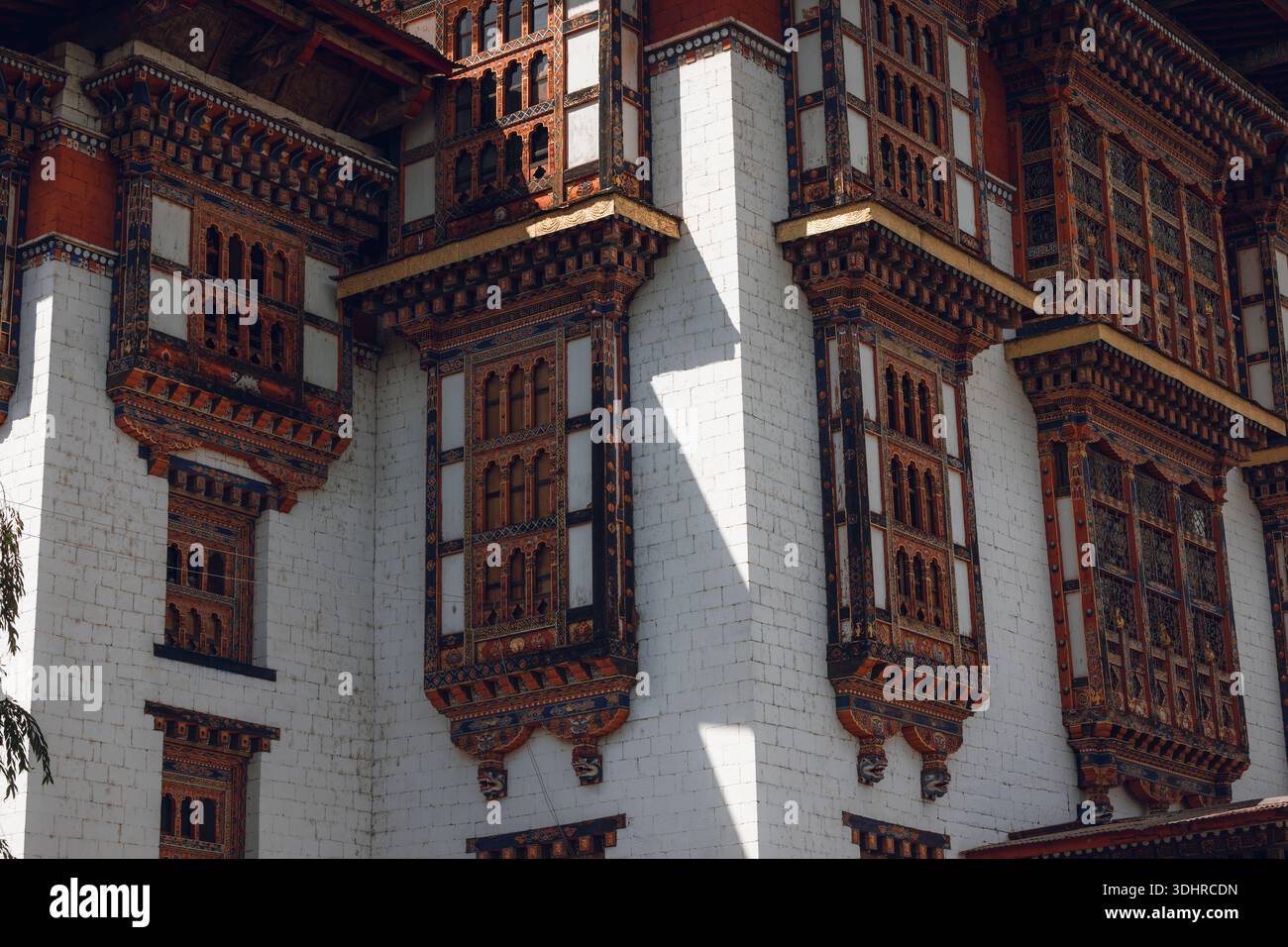 Vista delle intricate finestre in legno incorniciate da pareti di pietra bianca, che mostrano i dettagli meticolosi e la ricchezza culturale dell'architettura bhutanese, Jakar, Bumt Foto Stock