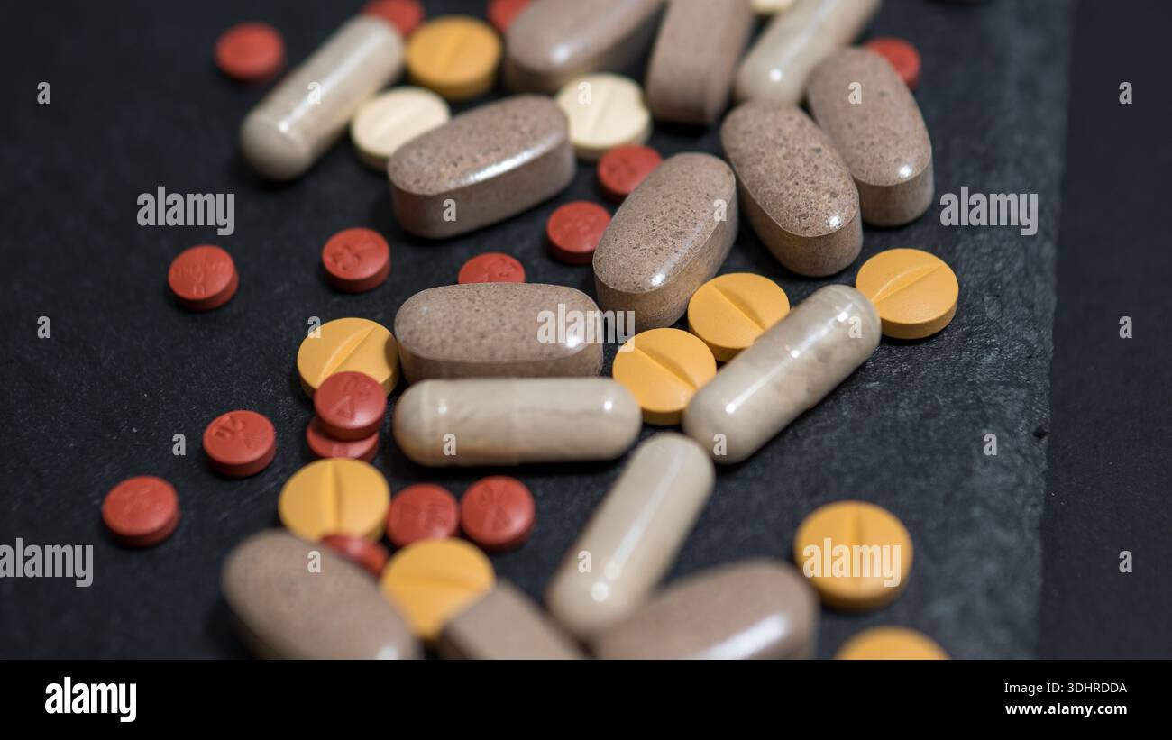 Pillole assortite, compresse e capsule su sfondo scuro, concetto farmaceutico Foto Stock