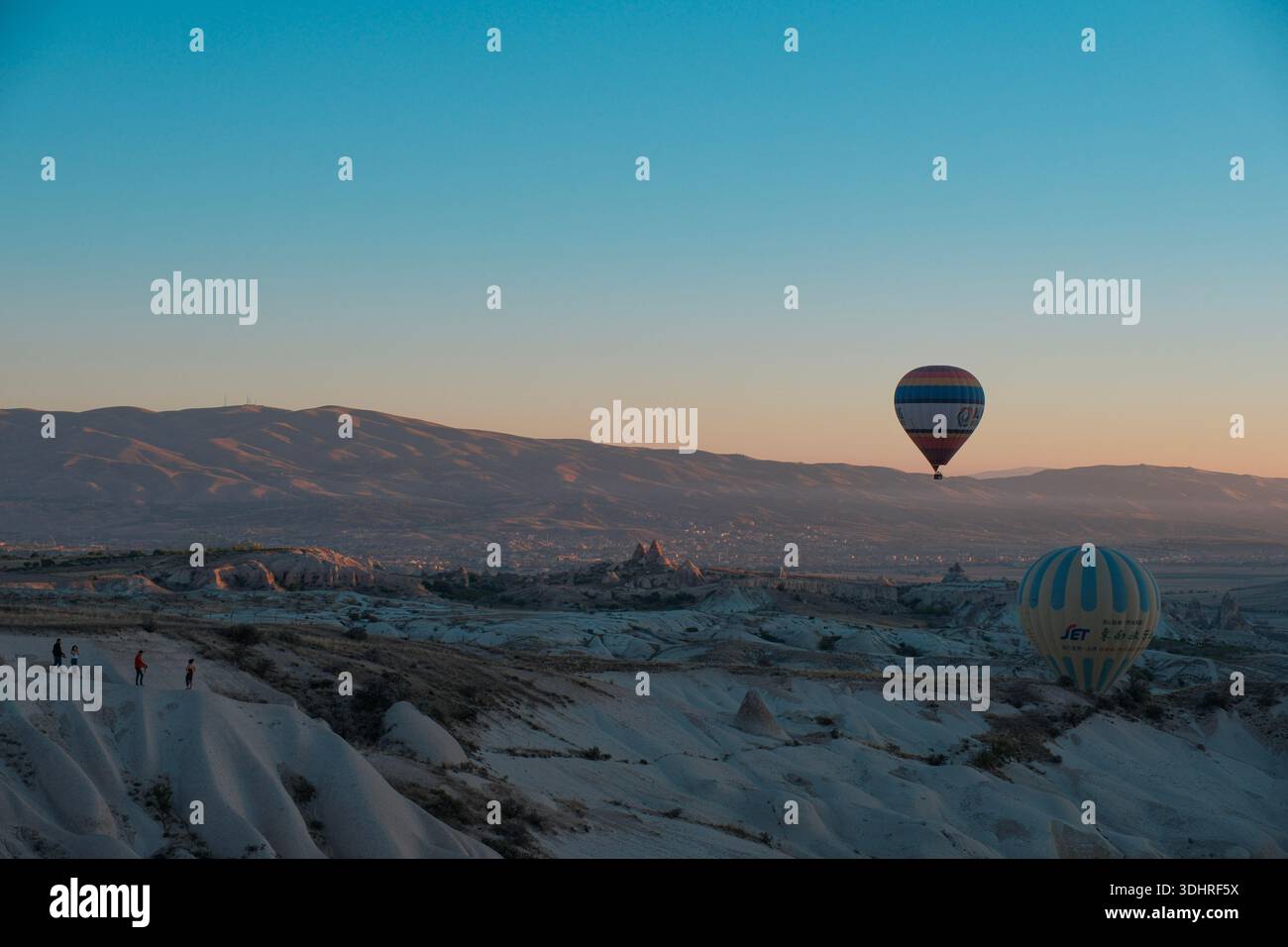 Cappadocia, Türkiye - 3 ottobre 2024: Palloni aerostatici fluttuano sul paesaggio roccioso della Cappadocia durante un tour in mongolfiera all'alba Foto Stock
