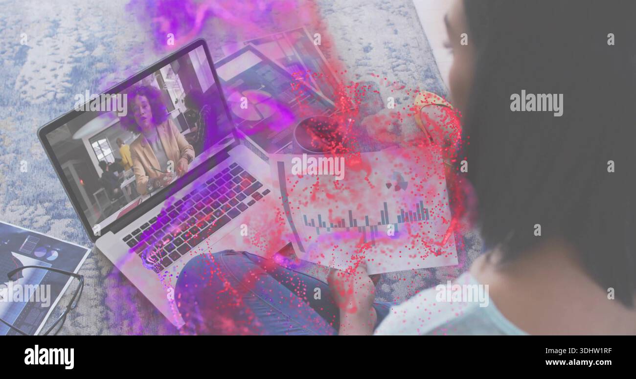 Donna che studia con la parte superiore azzurra che tiene le carte mentre guarda il laptop su un tappeto a motivi geometrici, la casa, lo spazio di copia Foto Stock