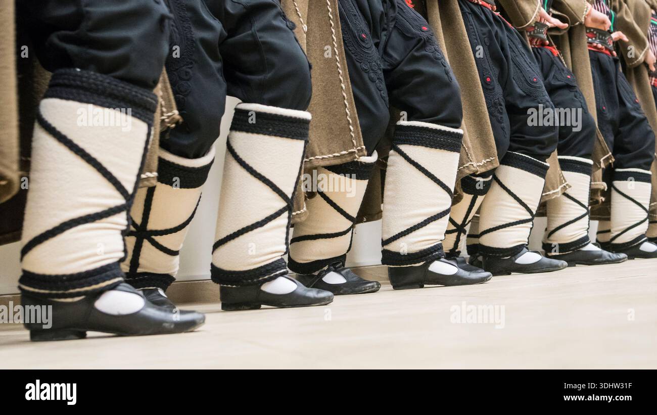 Ballerini popolari bulgari tradizionali che si esibiscono in autentici costumi etnici, con scarpe Tsarvuli in pelle nera e avvolgimenti per gambe in lana. Foto Stock