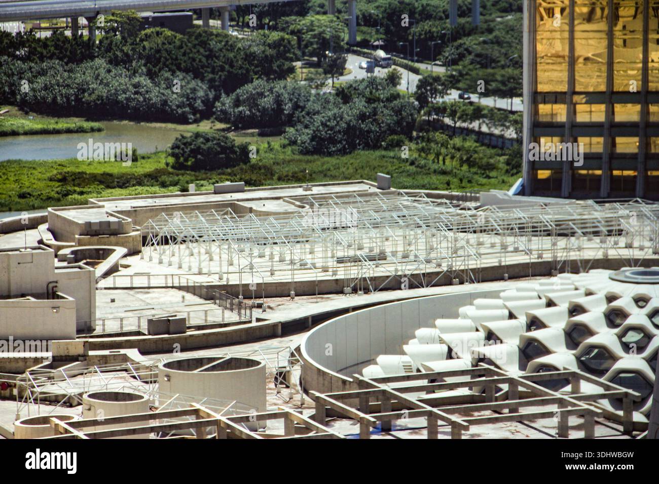 Moderna architettura urbana caratterizzata da cornici in acciaio bianco e strutture in cemento adagiate sullo sfondo di lussureggianti parchi verdi e un edificio in oro. Foto Stock