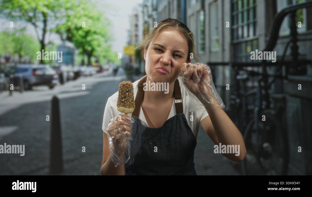 La donna che tiene il papavero con i guanti attacca la lingua con la sporcizia per strada; disgusta la sicurezza alimentare. Foto Stock
