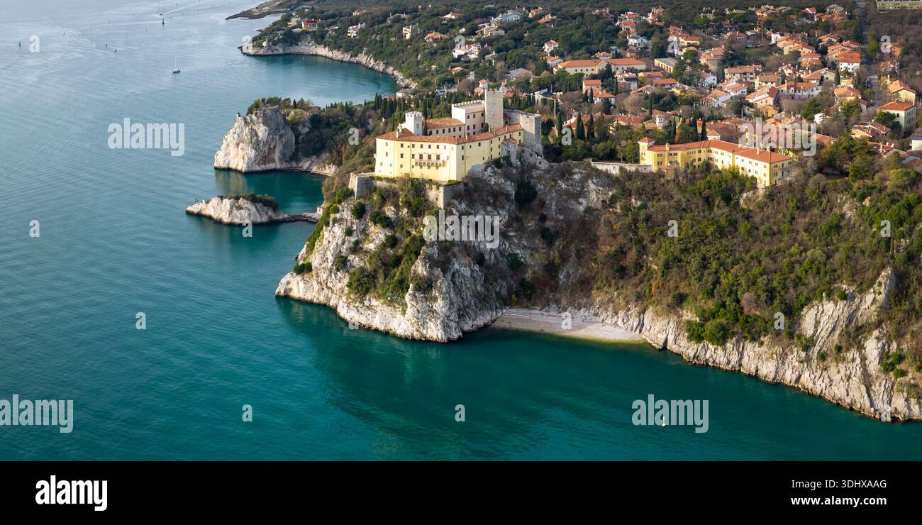 Vista panoramica aerea del Castello di Duino su alte scogliere calcaree con mare Adriatico e villaggio costiero Friuli Venezia Giulia Italia Foto Stock
