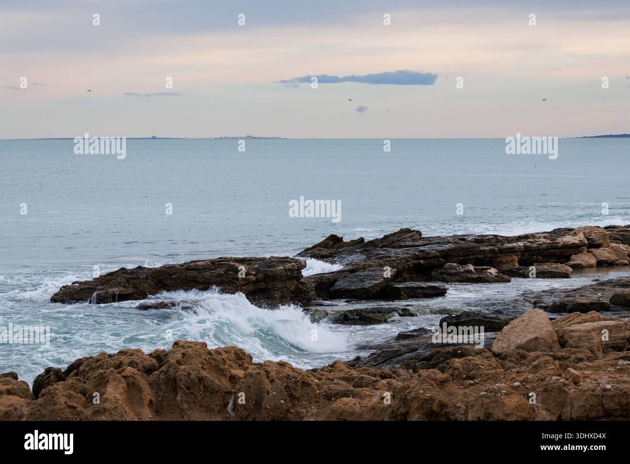 Paesaggio marino con tonalità pastello del tramonto dalla spiaggia di Agua Amarga e dall'isola di Tabarca all'orizzonte, Spagna Foto Stock