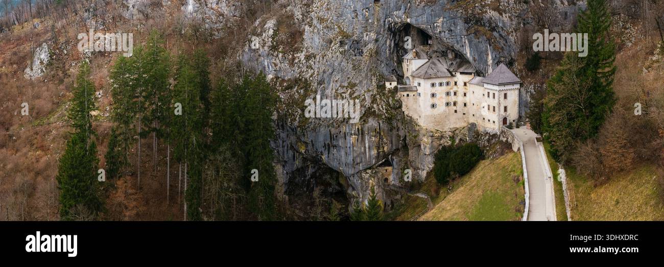 Epico panorama aereo del castello di Predjama: Fortezza rinascimentale medievale costruita in una bocca di grotta, punto di riferimento della Slovenia, senza persone Foto Stock