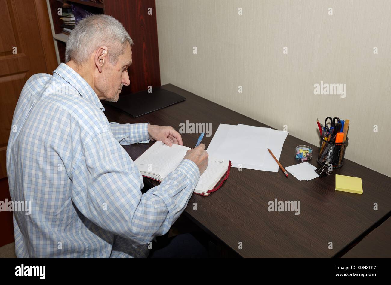 Un uomo anziano che scrive diario. Uomo che scrive con penna a tavola di legno, scrive appunti, diario Foto Stock