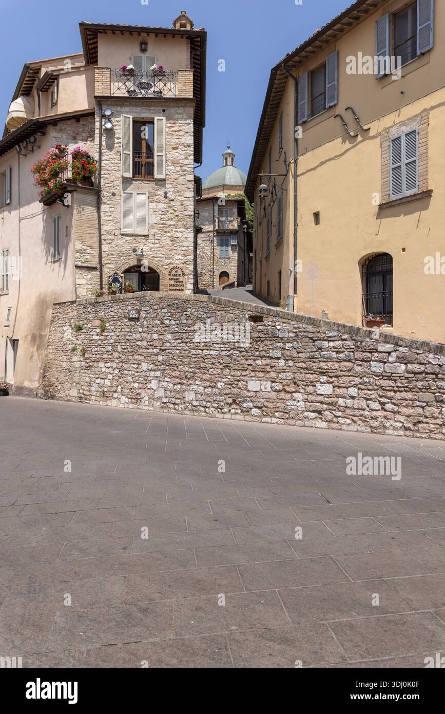 Assisi; Italia - 12 giugno 2025: Veduta di Piazza Santa Clara (Piazza Santa chiara) con tipiche case in pietra. Incantevole piazza con vasi di fiori Foto Stock