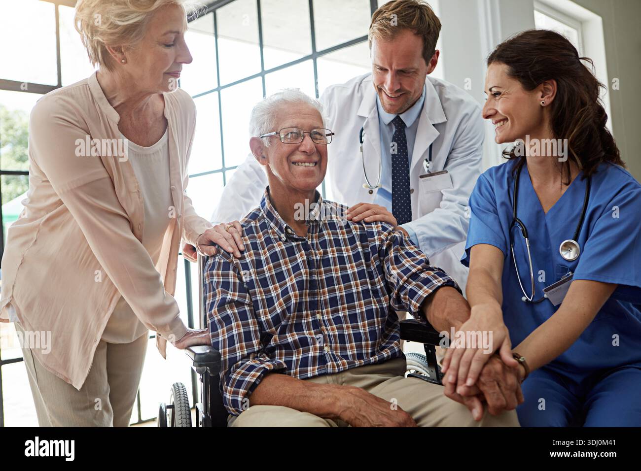Felice, medico e infermiere con senior man in clinica infermieristica per discussione di salute insieme. Coppia, check-up e paziente anziano di sesso maschile in sedia a rotelle Foto Stock