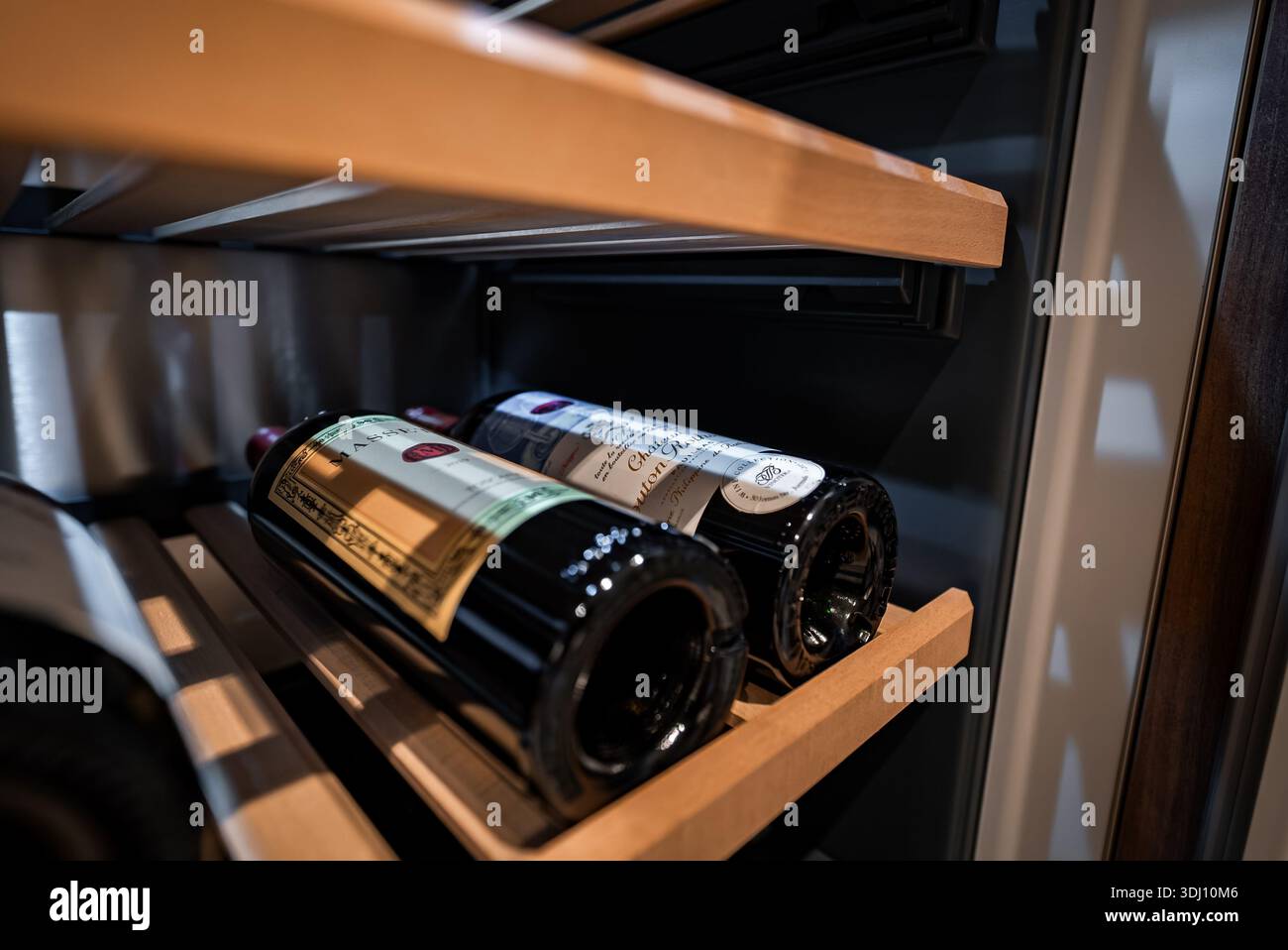 Due bottiglie di vino di prima qualità su spranghe di legno all'interno di un refrigeratore integrato Foto Stock