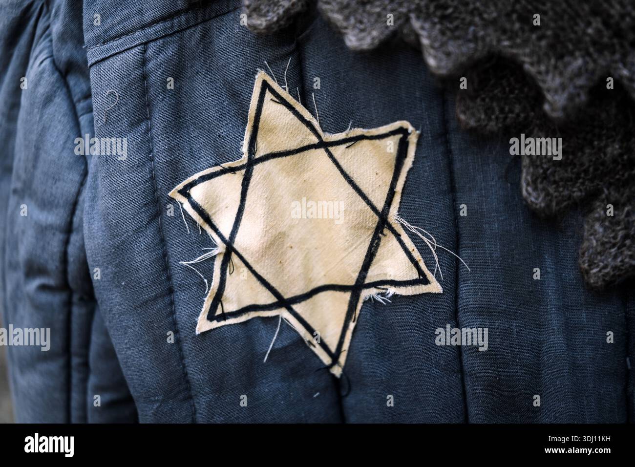 Un primo piano di un distintivo giallo Star of David cucito sul petto di un prigioniero di campo di concentramento o abiti di un abitante del ghetto degli anni '1940, Symboliz Foto Stock