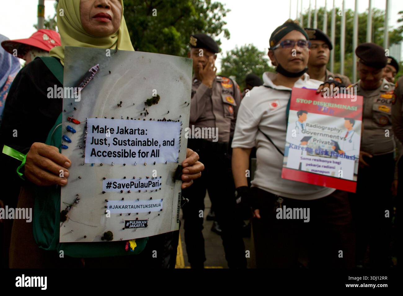 Giacarta, Indonesia. 10 dicembre 2025. I manifestanti hanno dei cartelli che chiedono una Giacarta giusta e accessibile mentre la polizia si trova nelle vicinanze. Foto Stock