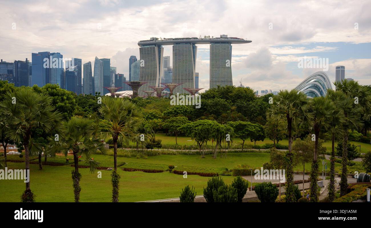 Una vista di Marina Bay Sands e dei grattacieli di Singapore centrale, con i giardini vicino alla baia in primo piano che mostrano gli alberi e i campi verdi Foto Stock