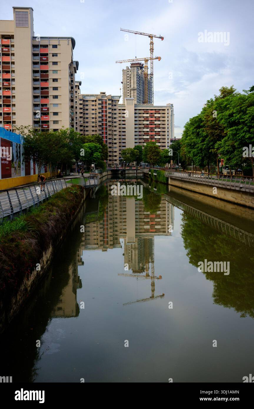 Un riflesso della costruzione di un alto edificio in HDB nel Rochor Canal che mostra la costruzione di King Georges Heights Singapore in lontananza. Foto Stock