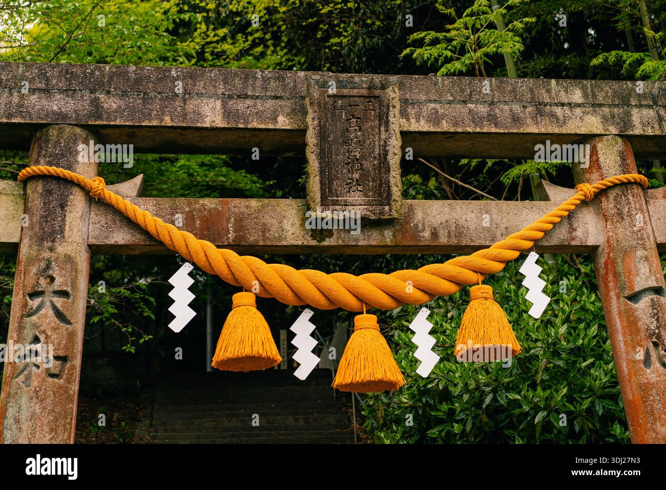 shikoku, giappone - 3 agosto 2025 porta torii shintoista decorata con una corda sacra shimenawa e strisce di carta da shice. Foto di alta qualità Foto Stock