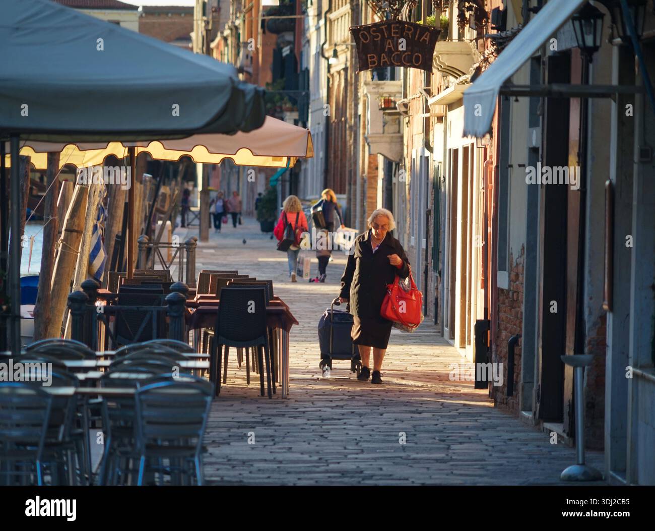 Cannaregio Venice Street, donna anziana che porta ad omero il suo shopping, la vita dura Italia Foto Stock