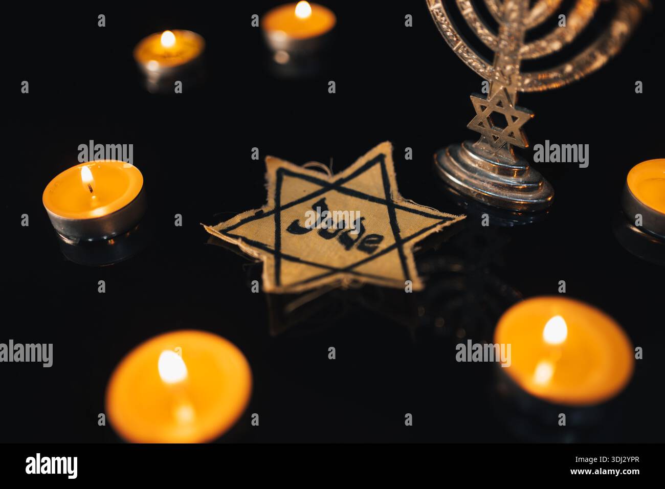 La stella di Davide e la candela si erge sulla tavola su uno sfondo nero in memoria delle vittime dell'Olocausto e il genocidio. Foto Stock
