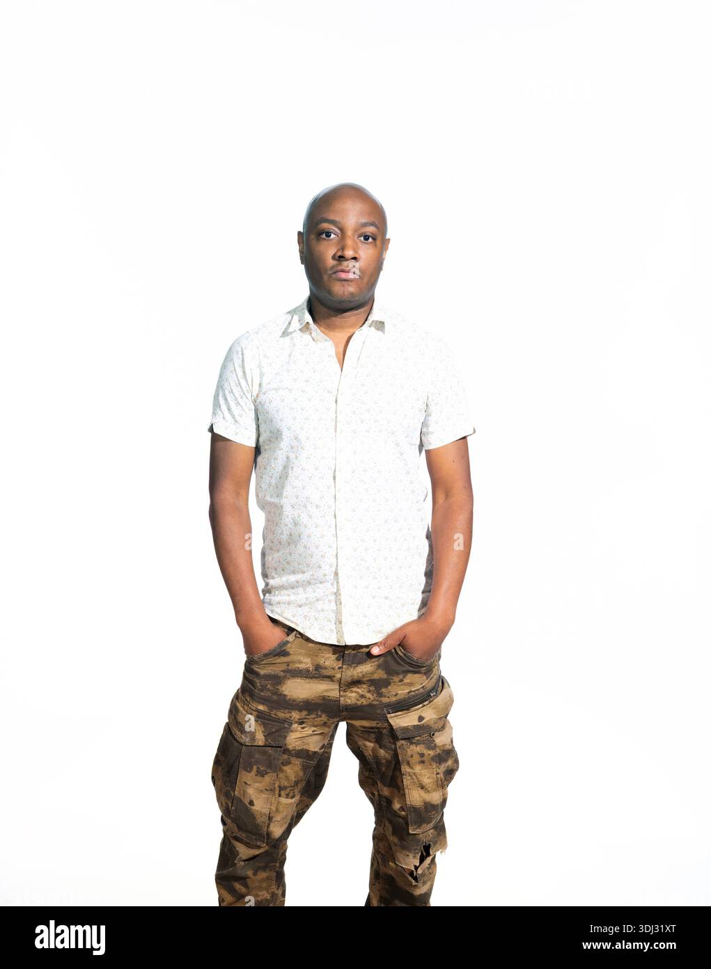Ritratto professionale di un giovane uomo sicuro di sé che indossa camicia bianca casual e pantaloni mimetici in stile militare, illuminazione brillante, sfondo bianco pulito, Foto Stock