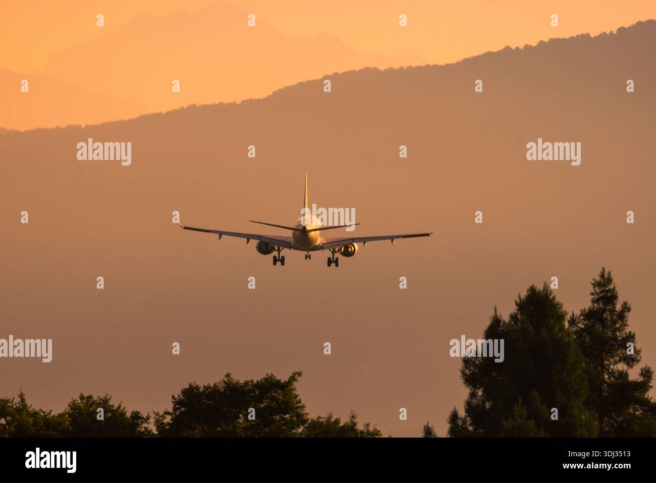 Aereo commerciale in avvicinamento alla pista durante un caldo tramonto, simbolo di viaggio, trasporto e connessione globale. Foto Stock
