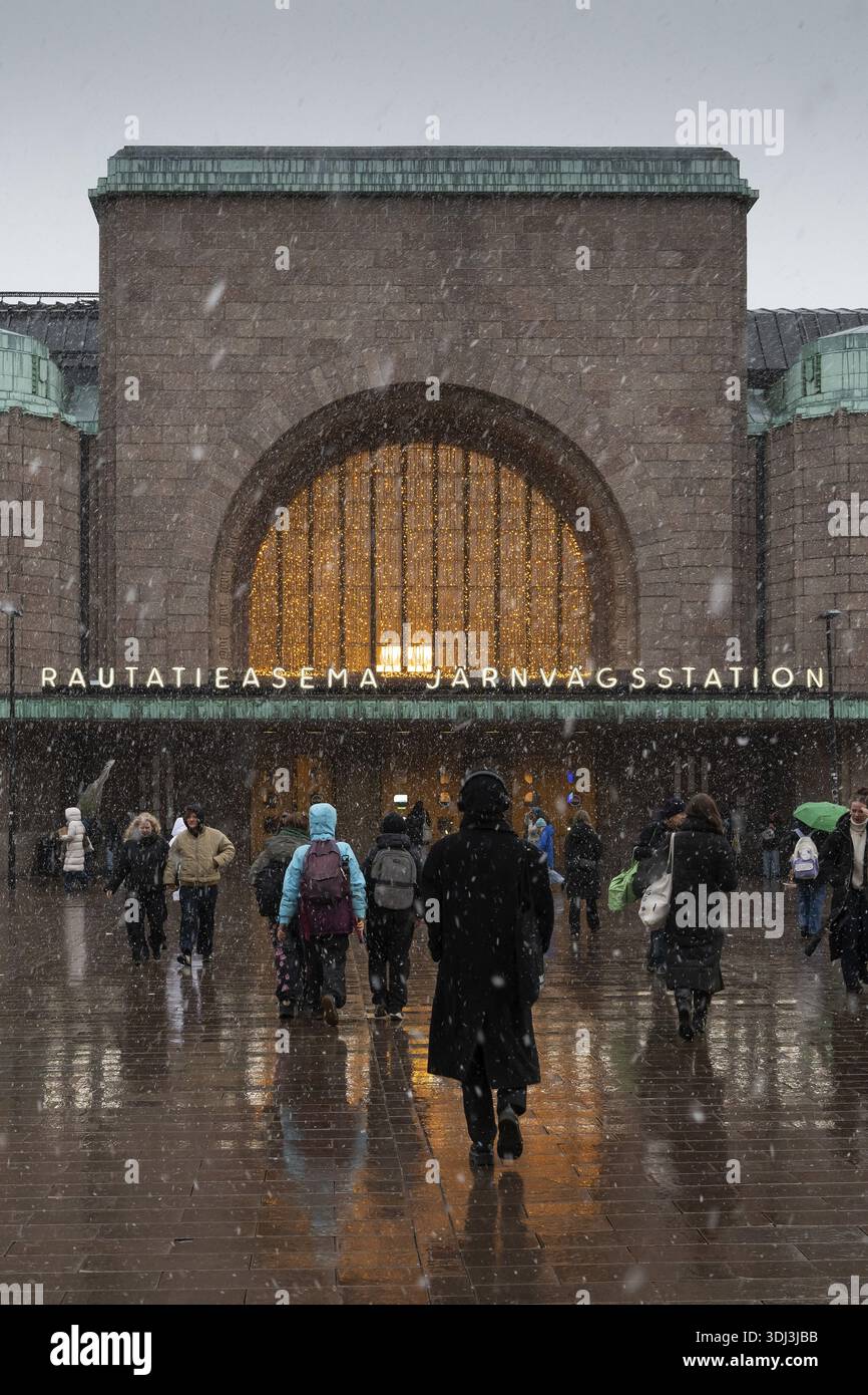 Ingresso laterale affollato alla stazione centrale con decorazioni natalizie durante le nevicate, Helsinki, Finlandia Foto Stock