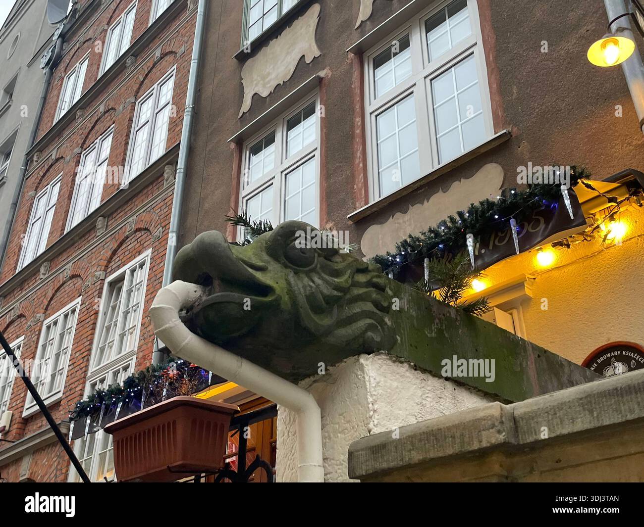 Getto d'acqua in gargoyle decorativo in pietra su una facciata storica di una casa cittadina nella città vecchia di Gdańsk, Polonia. - Immagine stock catturata con smartphone