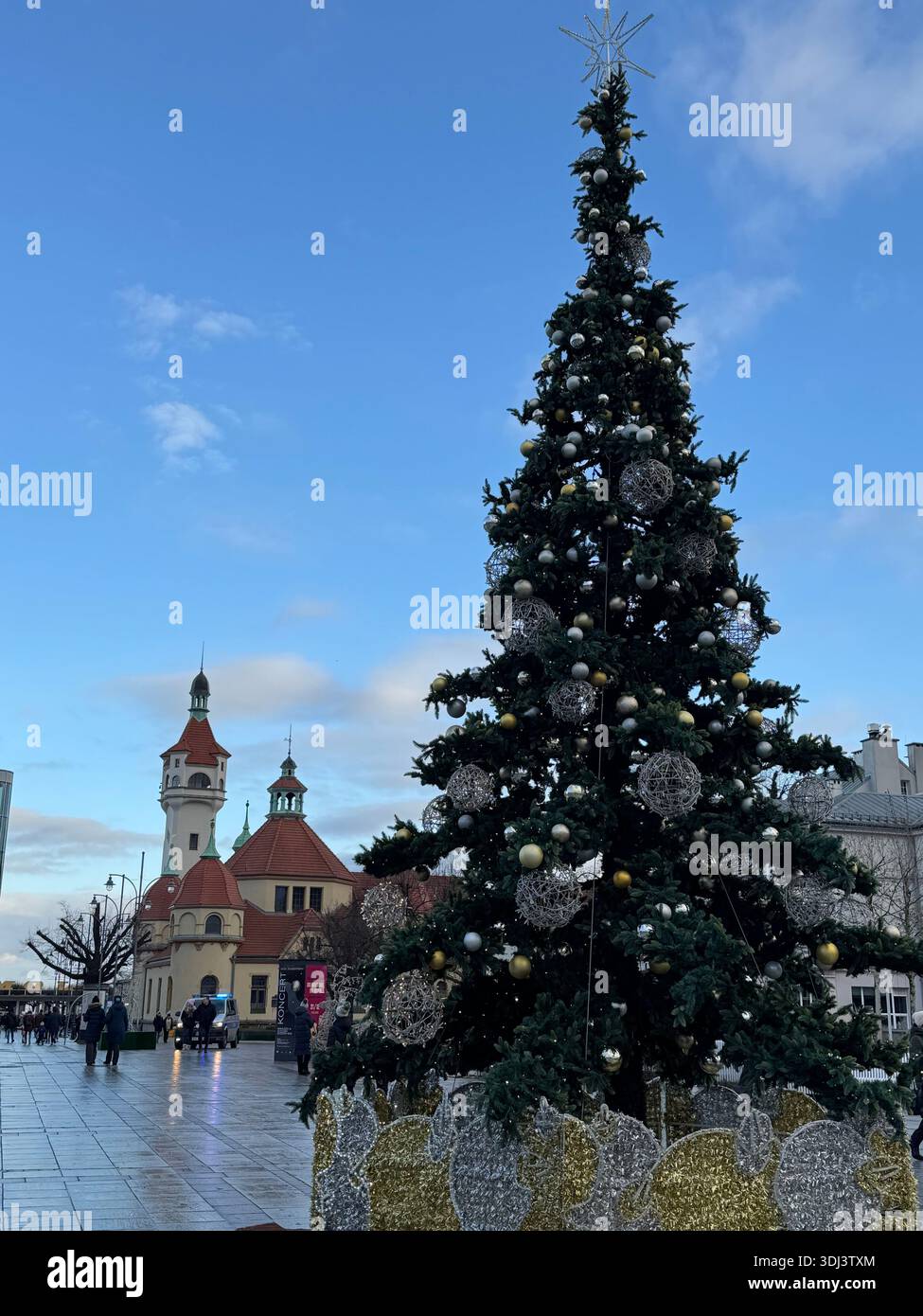 Albero di Natale decorato nel centro di Sopot con faro e chiesa sullo sfondo, Polonia. - Immagine stock catturata con smartphone