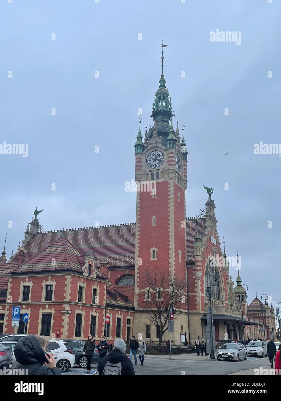 La storica stazione ferroviaria principale di Gdańsk, con la sua iconica torre dell'orologio, che mostra l'architettura in mattoni e che funge da importante punto di riferimento per i trasporti della città. - Immagine stock catturata con smartphone