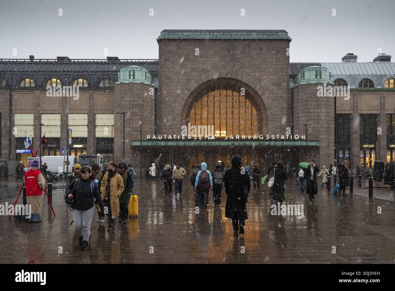 Ingresso laterale affollato alla stazione centrale con decorazioni natalizie durante le nevicate, Helsinki, Finlandia Foto Stock