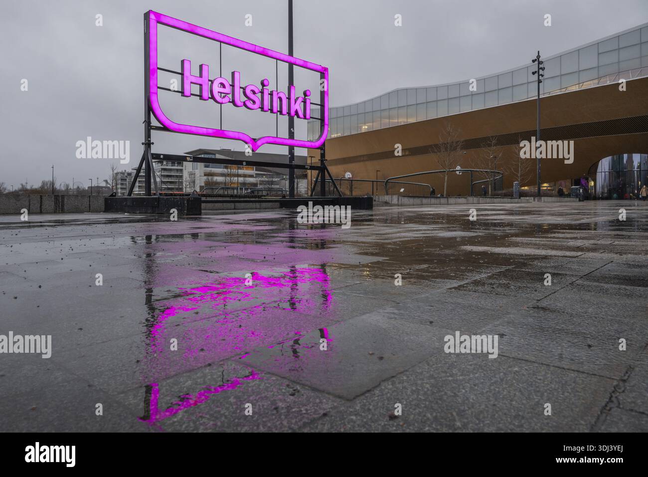 Grande logo rosa luminoso della città di Helsinki, di fronte alla Biblioteca centrale e al Centro culturale di Oodi, riflesso sul terreno bagnato, Helsinki, Finlandia Foto Stock