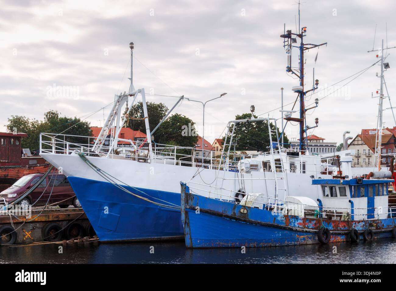 La vita marittima di tutti i giorni si concentra con la vista di barche da pesca ormeggiate che mostrano scafi usurati, vernice a strati e superfici di lavoro che definiscono il pratico charac del porto Foto Stock