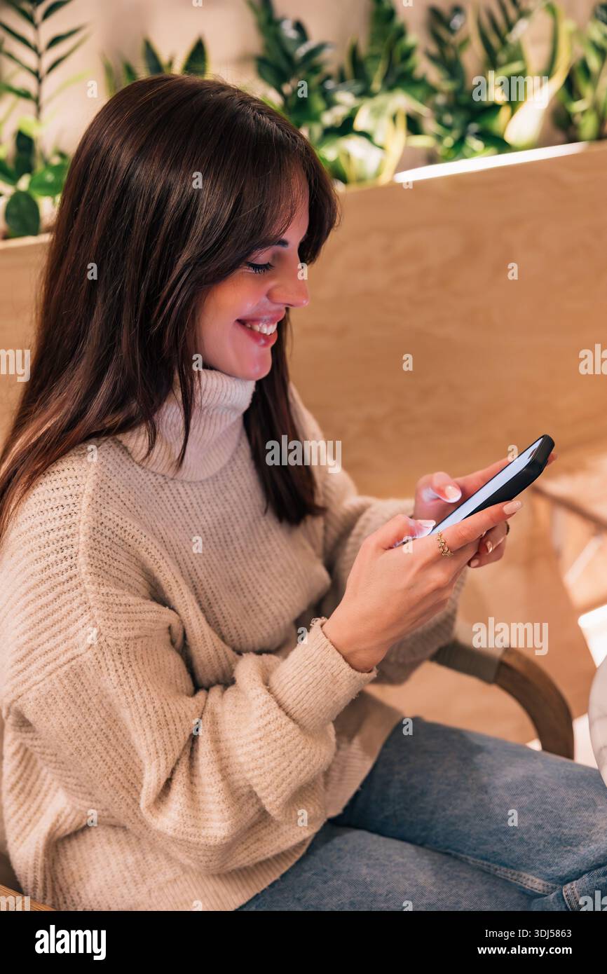 Donna sorridente mentre usa lo smartphone per comunicare Foto Stock