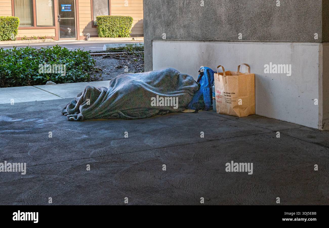 Una persona dorme sotto una coperta in un garage a Roseville, California. Foto Stock