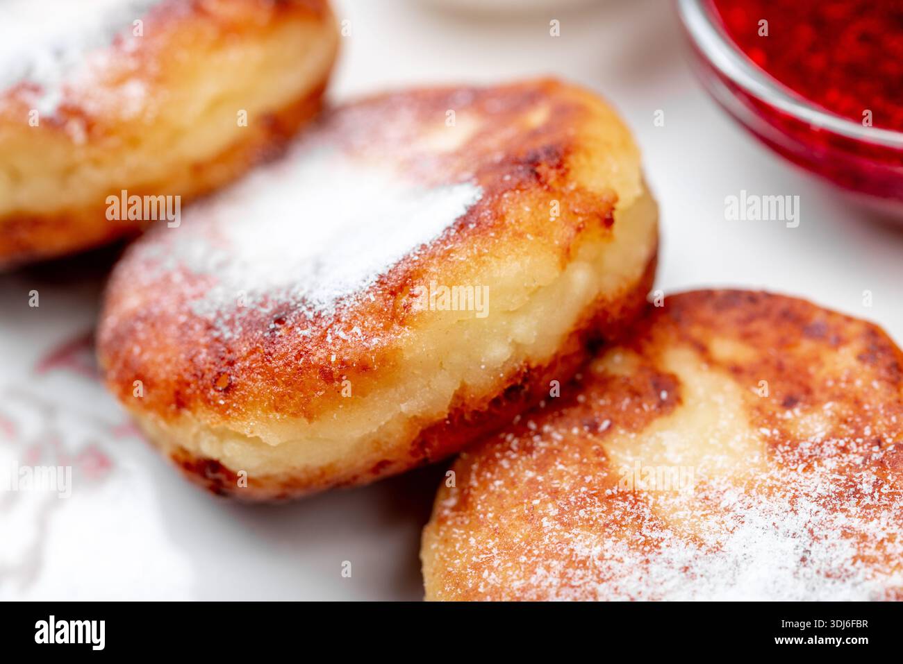 Primo piano di tre sciroppi dorati, una popolare colazione dell'Europa orientale o un piatto da dessert a base di quark/formaggio fresco, abbondantemente cosparso di Foto Stock