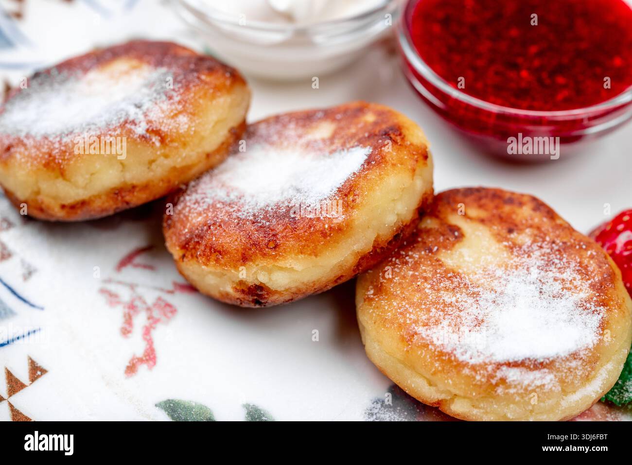 Primo piano di tre sciroppi dorati, una popolare colazione dell'Europa orientale o un piatto da dessert a base di quark/formaggio fresco, abbondantemente cosparso di Foto Stock