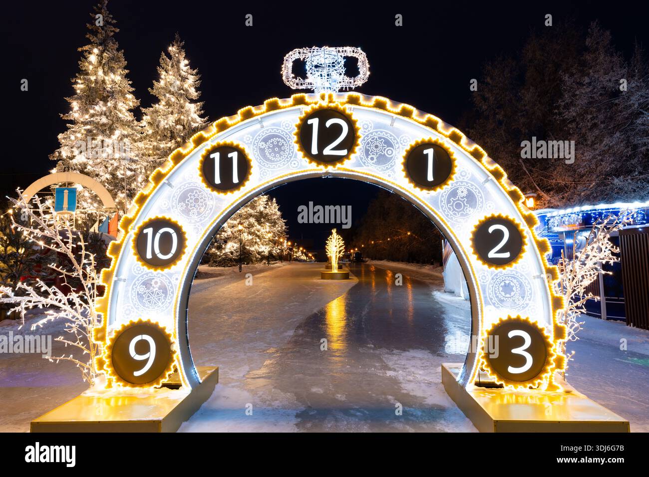 Ulyanovsk, Russia - 14 febbraio 2022: Enorme orologio di Natale in strada nell'illuminazione serale. Strada ricoperta di neve con decorazioni natalizie. Foto Stock
