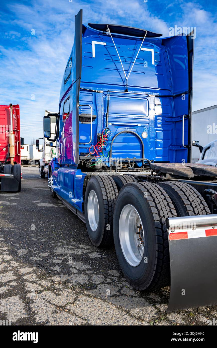 Trattore semi-camion blu Big RIG con cabina alta per il riposo del conducente e con doppi assali e ruote con pneumatici nuovi in piedi sul parcheggio di arresto i Foto Stock