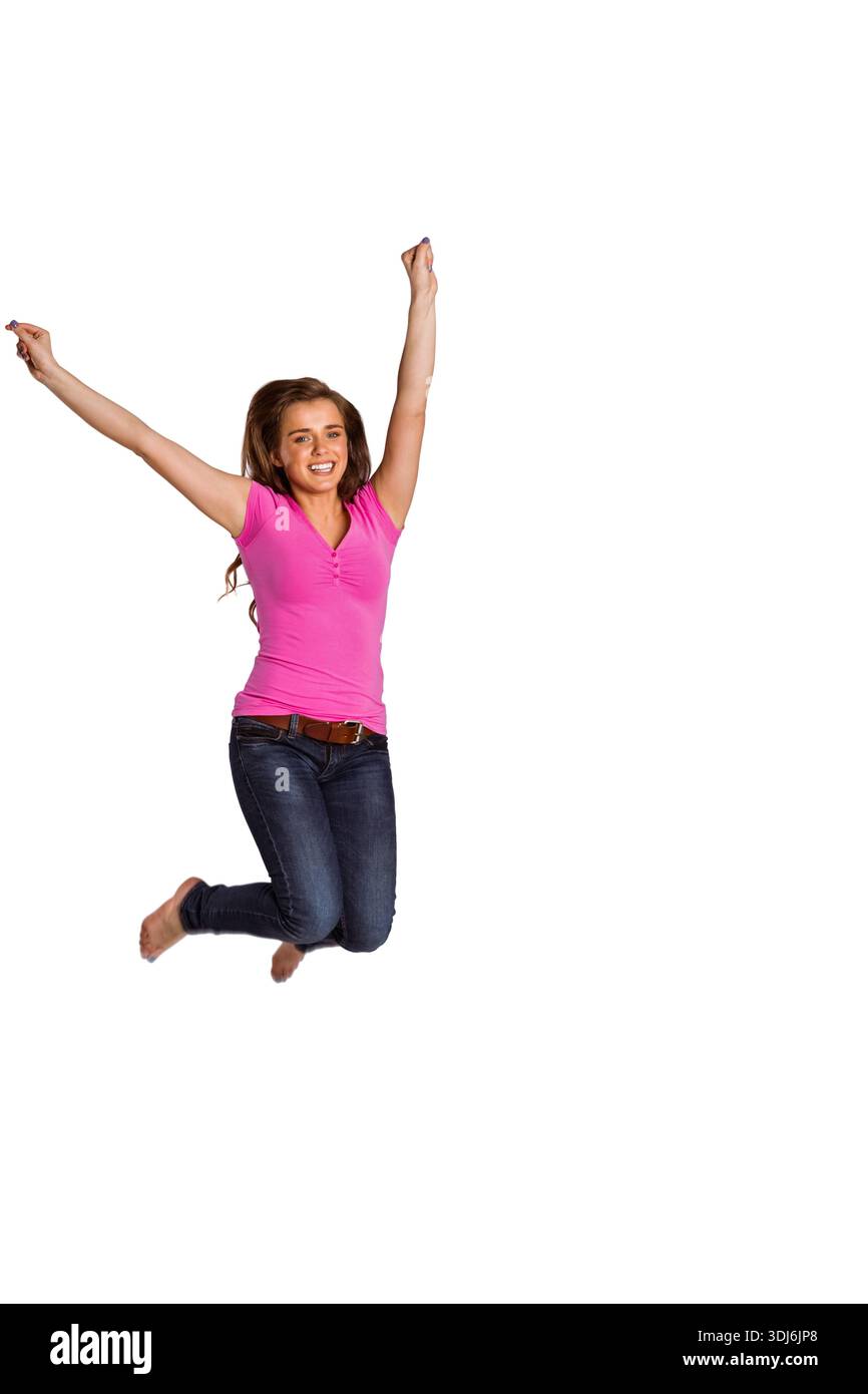Donna che salta in uno studio bianco con top rosa brillante e jeans scuri con cintura in pelle marrone. Donna, movimento, dinamico, energico, a piedi nudi, denim, ros Foto Stock