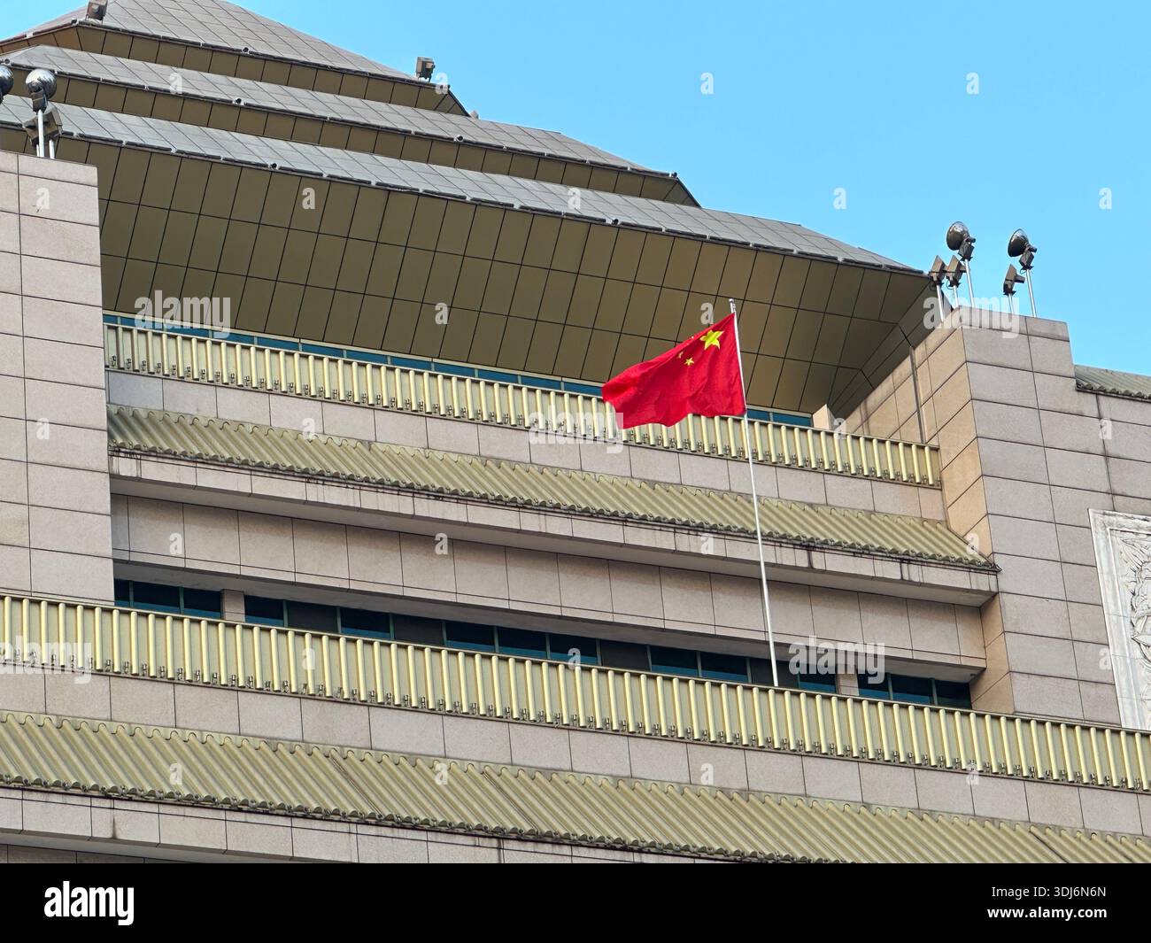 La bandiera nazionale della Cina ondeggia su un cielo blu limpido da un edificio moderno - Immagine stock catturata con smartphone