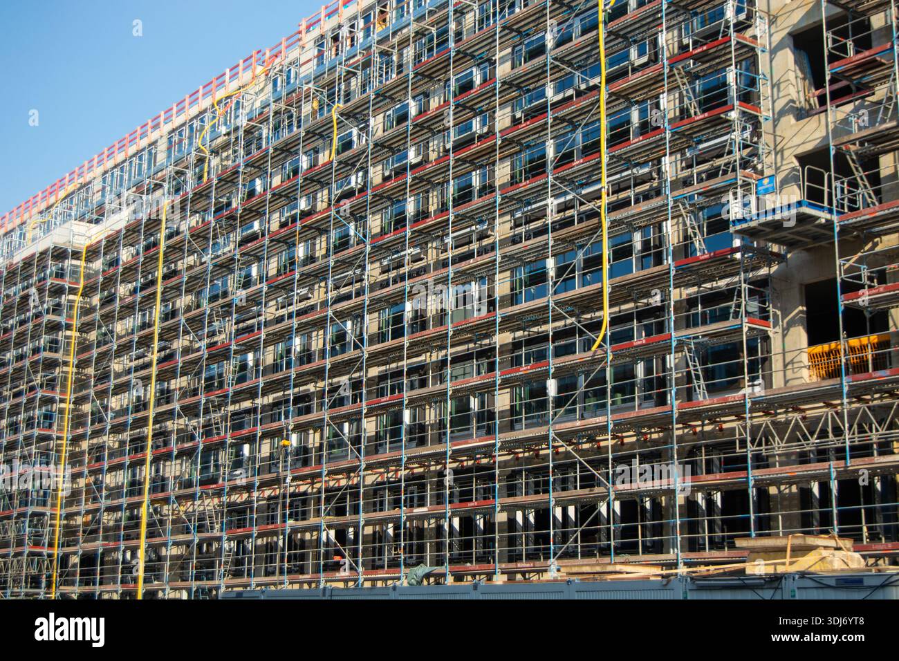 Un grande cantiere caratterizzato da un edificio in fase di ristrutturazione, con impalcature e numerose finestre Foto Stock