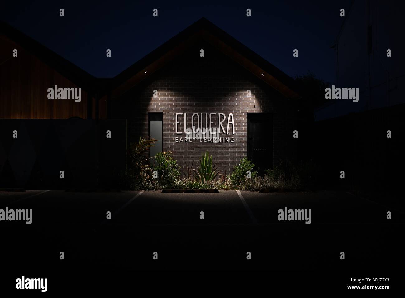 Insegna illuminata di Elouera Early Learning sul muro dell'edificio del centro di assistenza all'infanzia, di notte Foto Stock