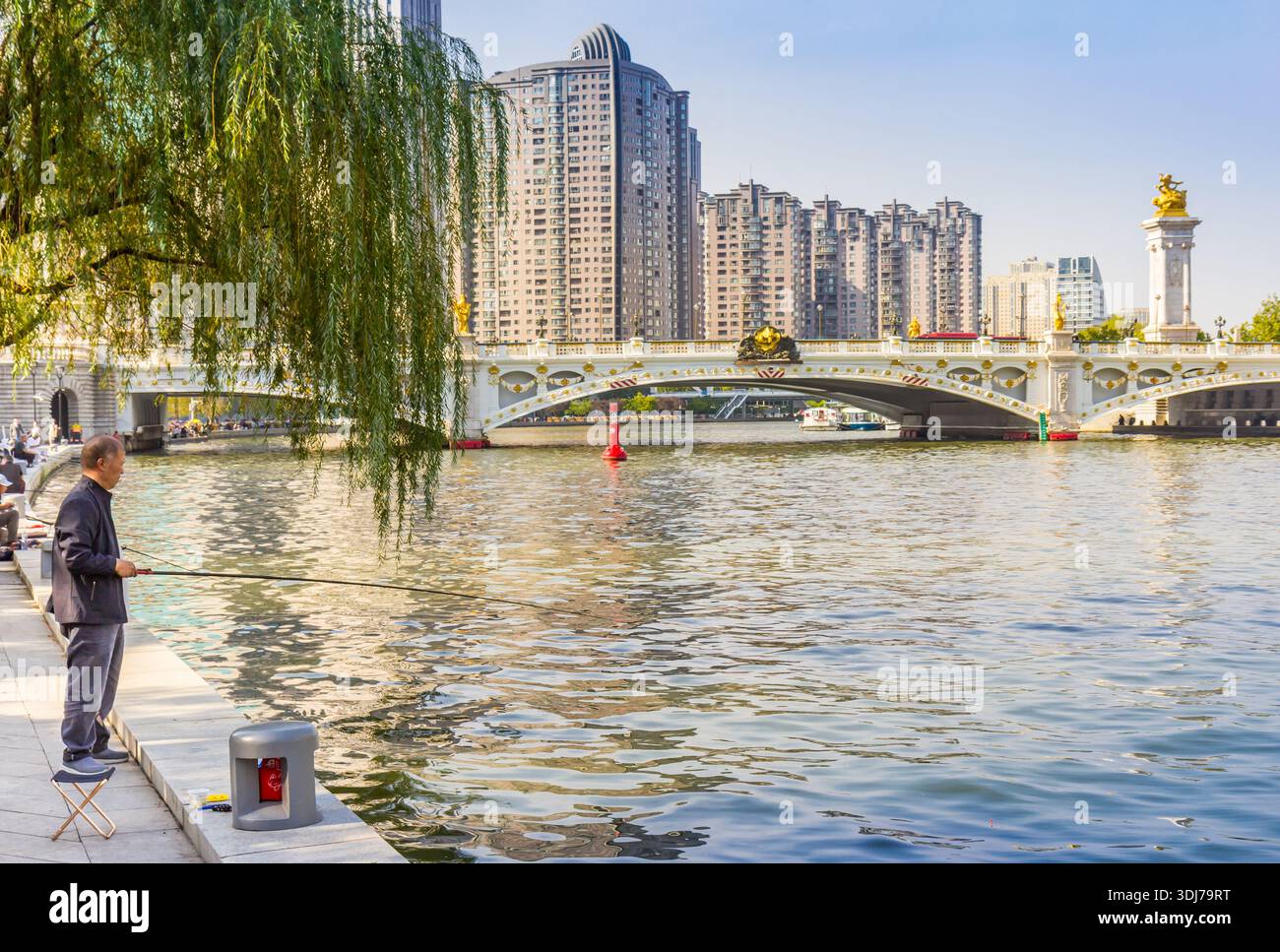 Pescatore sotto l'albero al fiume Haihe a Tianjin, in Cina Foto Stock
