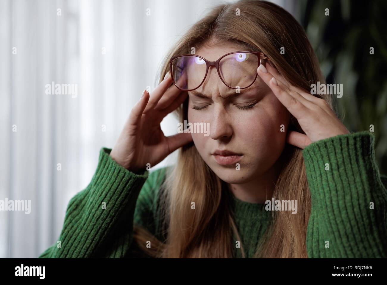 Giovane donna frustrato con gli occhiali che toccano le tempie, soffre di mal di testa o stress, occhi chiusi. Foto Stock