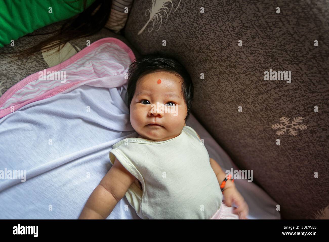 Pampanga, Filippine. 25 gennaio 2026. Neonato che indossa elementi protettivi contro l'usog, una credenza che si pensa possa causare una malattia nei neonati seguendo uno sguardo, un saluto o un complimento da parte di un visitatore: Un braccialetto con perle, un amuleto (noto come anting-anting o agimat) e un punto rosso sulla fronte. Queste pratiche, profondamente radicate nella cultura filippina, sono radicate in una combinazione stratificata di animisti pre-coloniali e sistemi di credenze sincretiche, e possibilmente influenzate dal mal de ojo spagnolo, il malocchio. Il controrituale principale si chiama lawayan...|Maggiori informazioni qui sotto|credito: Kevin Izorce/Alamy Live News Foto Stock