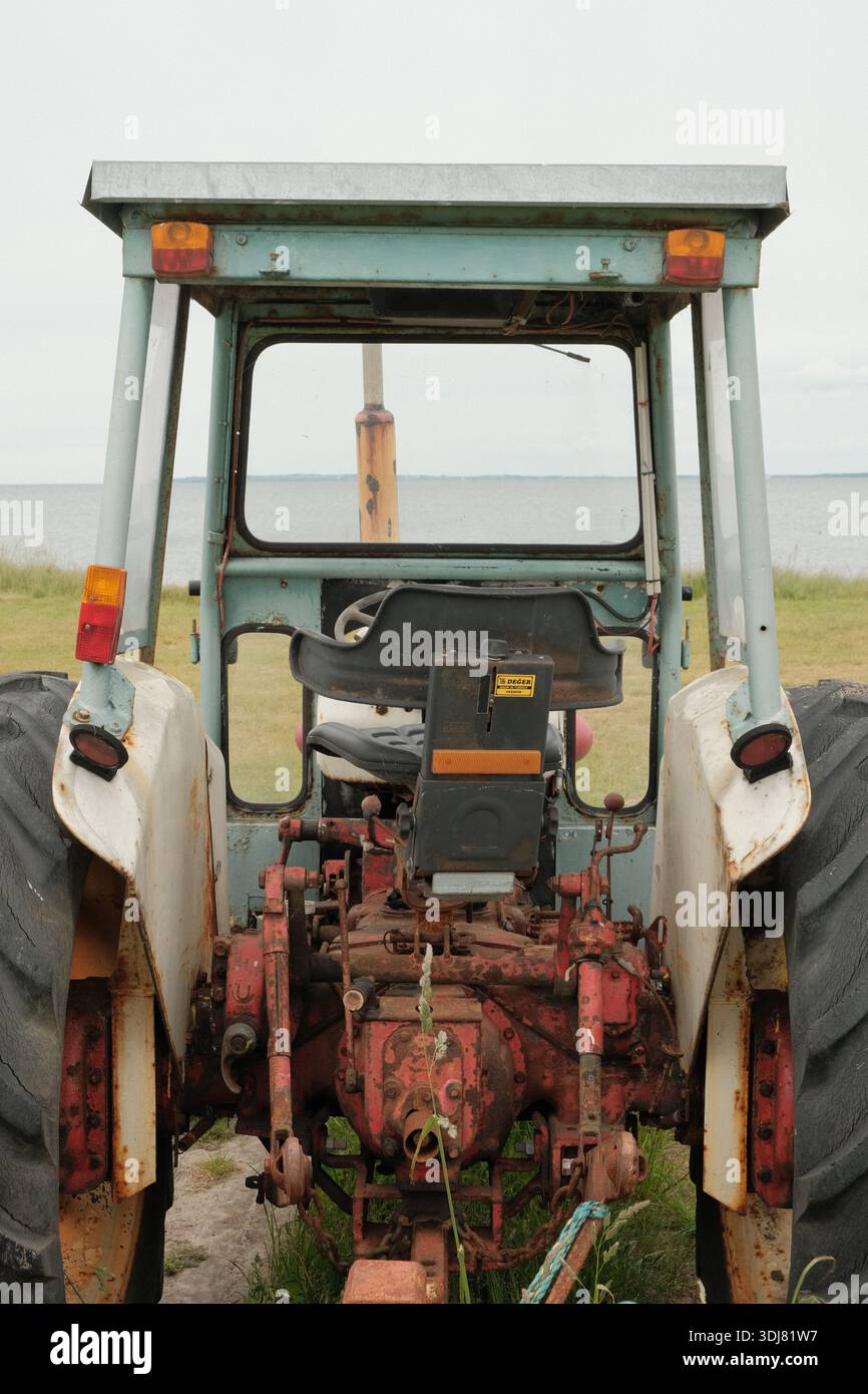 Vista posteriore di un vecchio trattore con componenti meccanici e superfici usurate, simbolo dell'agricoltura tradizionale e dell'industria rurale. Foto Stock