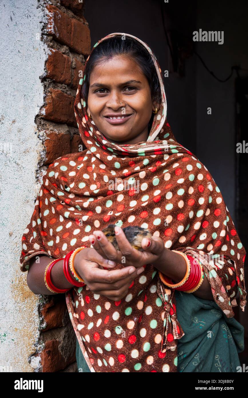 Ritratto di una giovane donna di Orissa rurale che tiene in mano una piccola pulcino, l'India Foto Stock