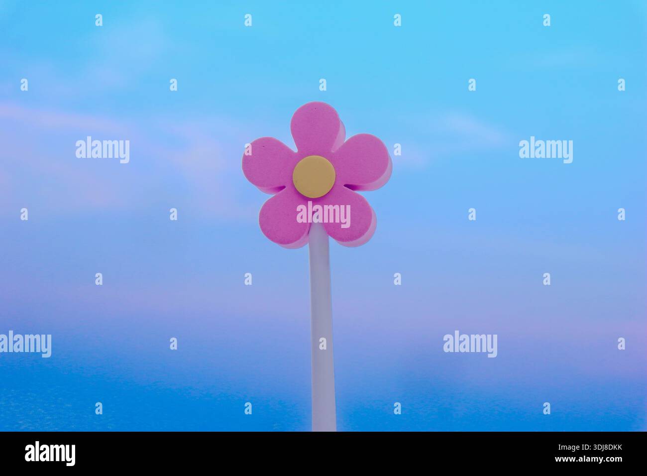 Giocattolo con fiori in schiuma rosa minimalista contro un cielo radioso cerulese e viola. Sfondo estivo da sogno per design creativi. Foto Stock