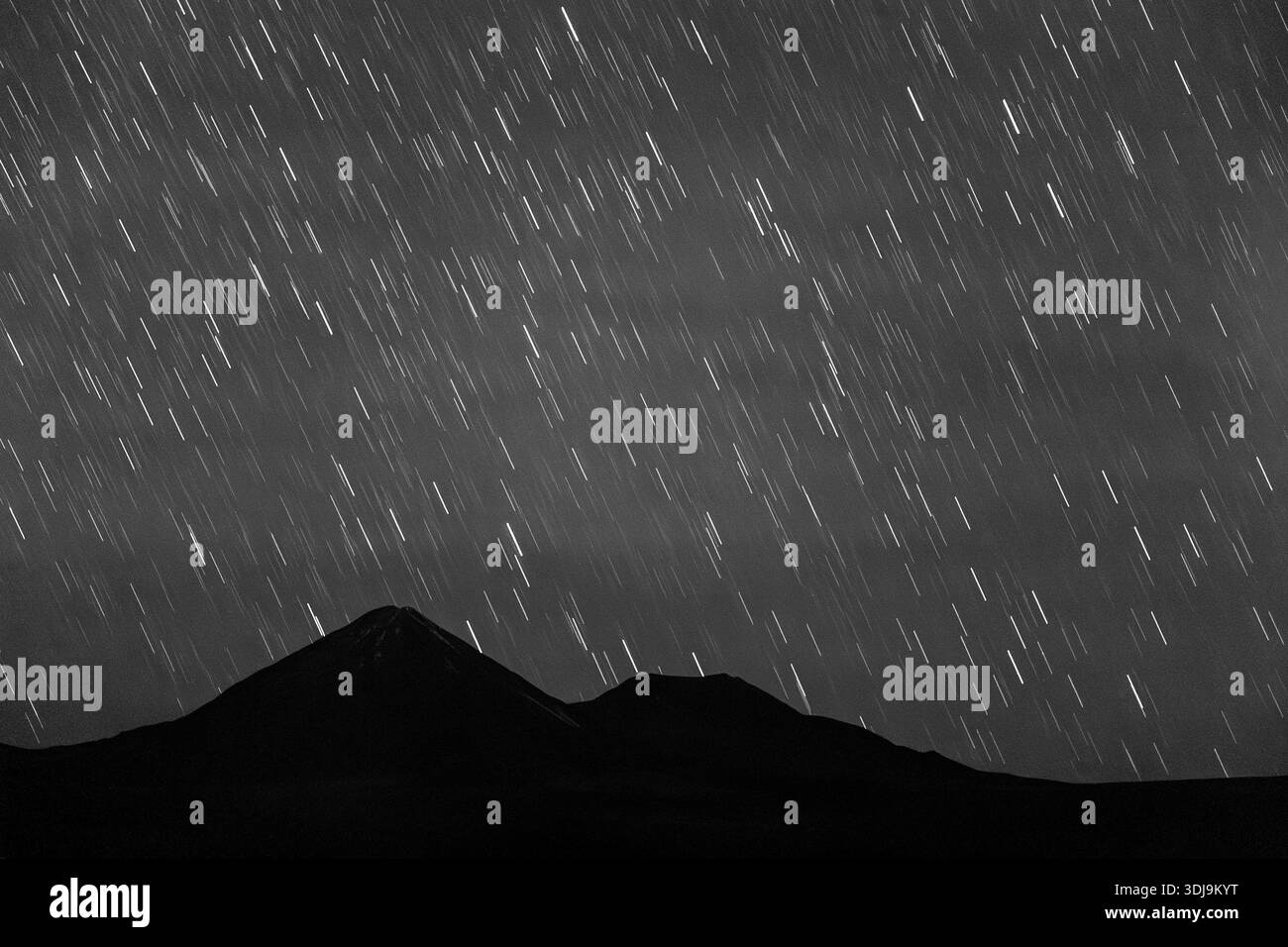 Star Trail sopra una catena montuosa e un vulcano in Cile in bianco e nero Foto Stock