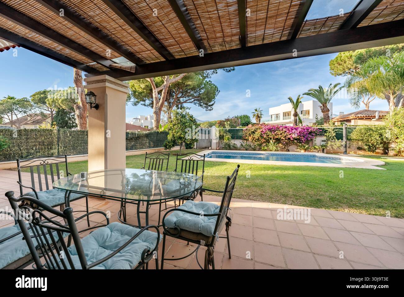 un'immagine di un tavolo da pranzo in vetro all'aperto e di una piscina nel giardino di una villa mediterranea di lusso Foto Stock