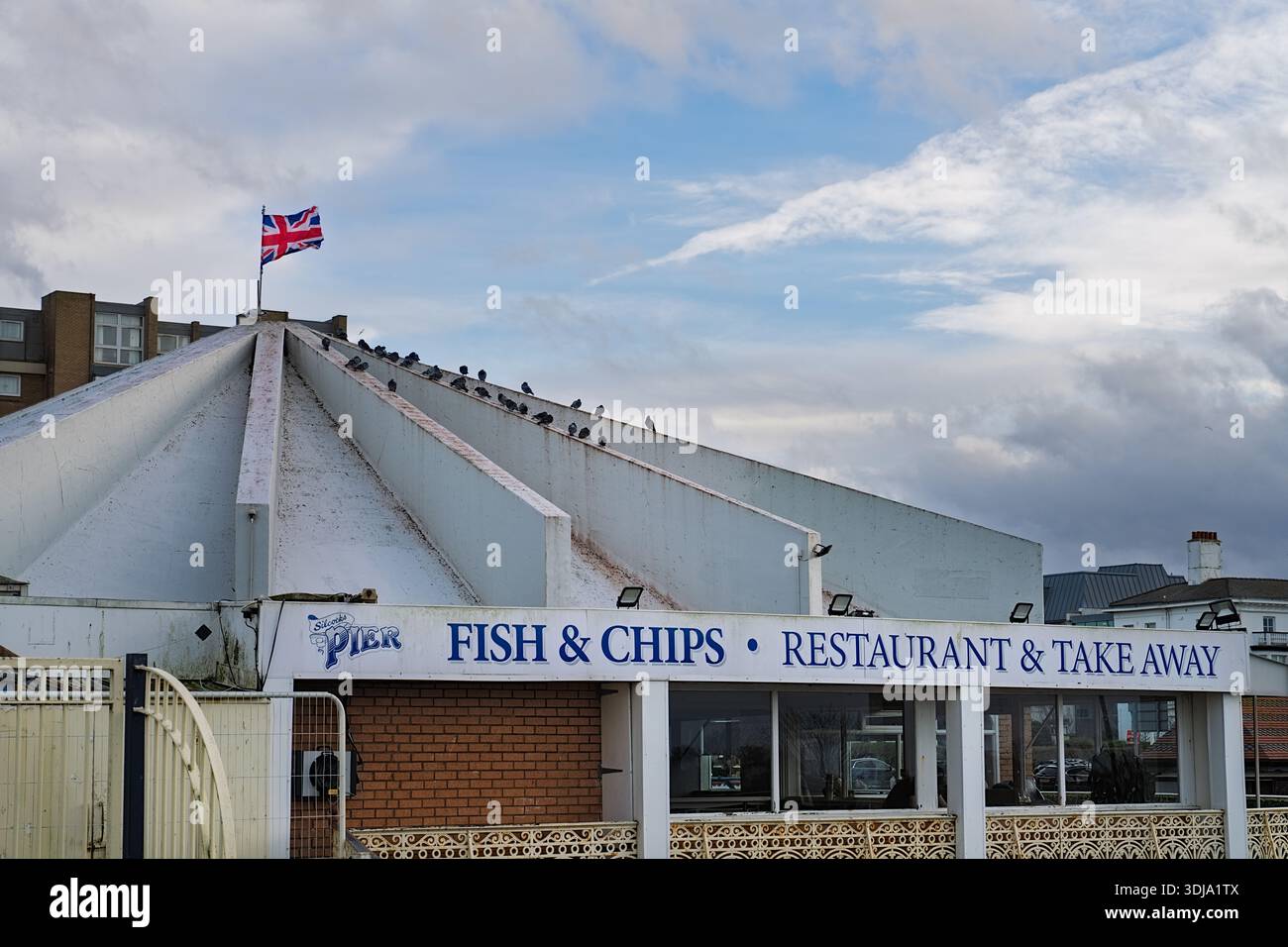 Southport, Regno Unito, 24 gennaio 2026: Un ristorante di pesce e chip a Southport con una bandiera union Jack sopra di esso. Ci sono degli uccelli sul tetto Foto Stock