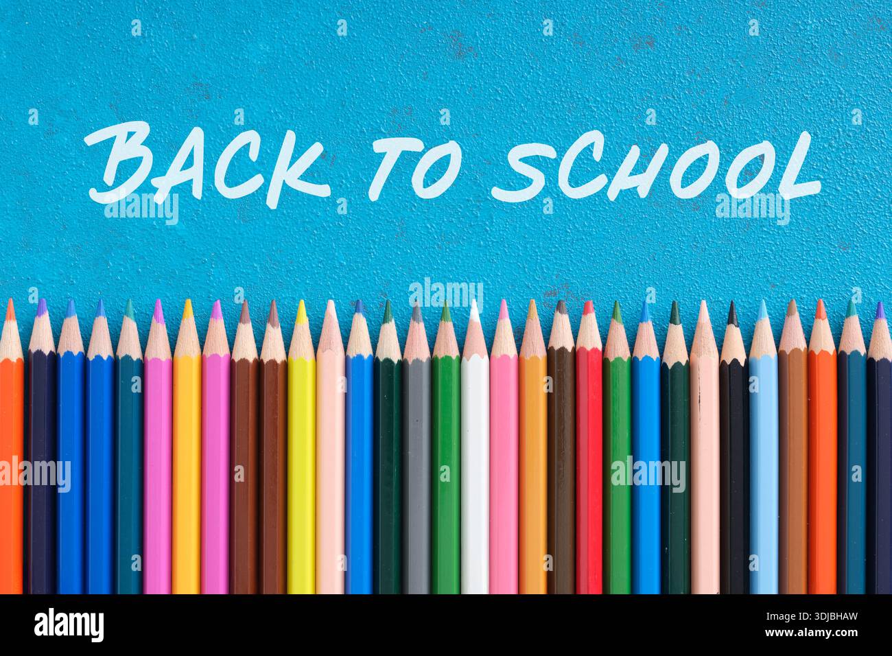 Matite colorate che formano una linea orizzontale su uno sfondo blu con la scritta di ritorno a scuola. Foto Stock